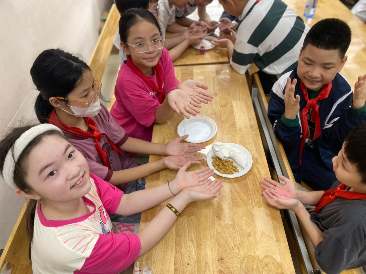 A group of children sitting at a table with their hands on a plate

Description automatically generated
